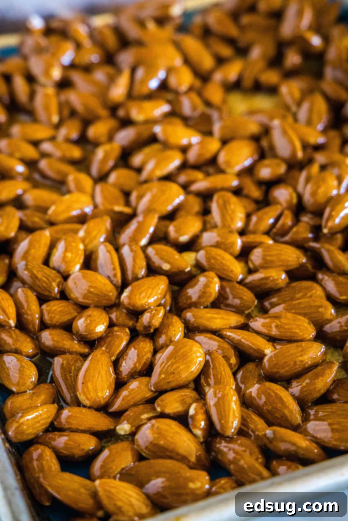 Sweet Heat Honey Roasted Almonds 3 Spicy honey roasted almonds spread in a single layer on a parchment-lined baking sheet, ready for the oven.