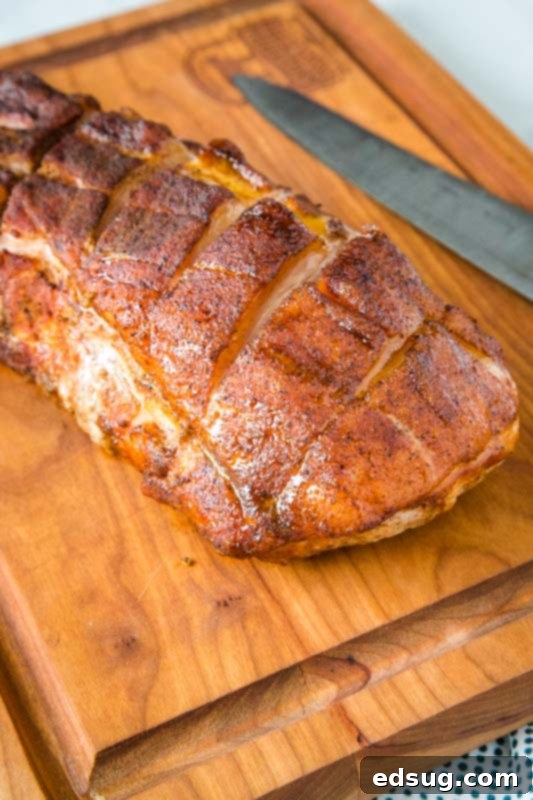 whole pork loin roast on a cutting board with a knife