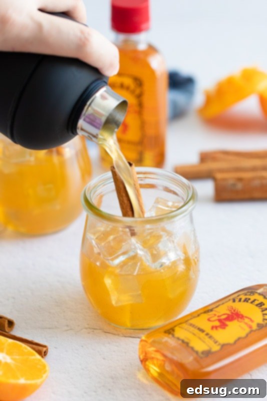 pouring apple cider cocktail from shaker to a glass