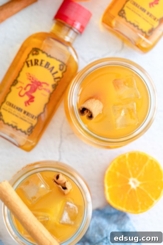 apple cider drink in glasses with bottle of fireball near by