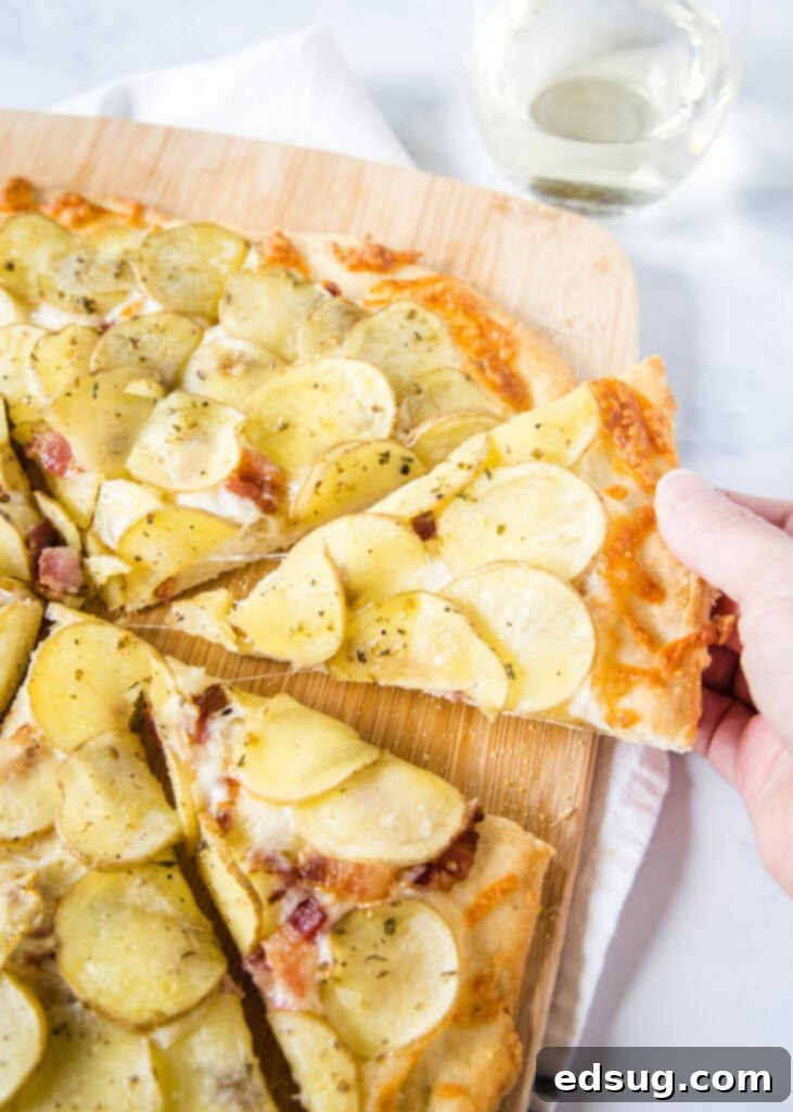 Golden Potato Pizza 2 A golden-brown slice of potato pizza being lifted from a cutting board, showcasing its crispy crust, melted cheese, and perfectly cooked potato slices.