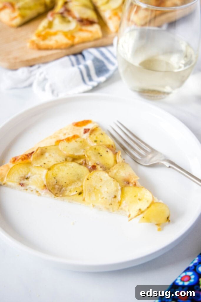Golden Potato Pizza 3 A delectable slice of potato pizza resting on a white plate with a fork, highlighting the vibrant toppings and inviting texture.