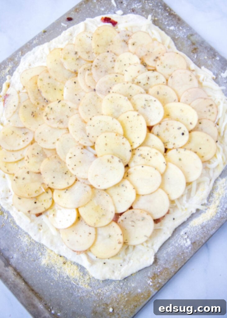 Golden Potato Pizza 5 An unbaked potato pizza, perfectly topped with thin potato slices, cheese, and bacon, ready to go into the hot oven.