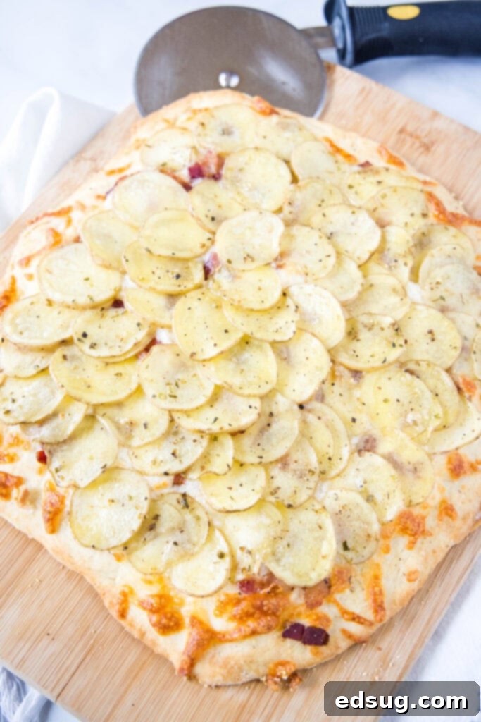 Golden Potato Pizza 6 A beautifully baked potato pizza on a wooden cutting board, with a pizza cutter poised to slice, inviting a delicious first bite.