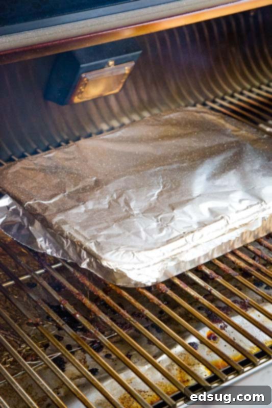 pan wrapped in foil on a grill, smoking