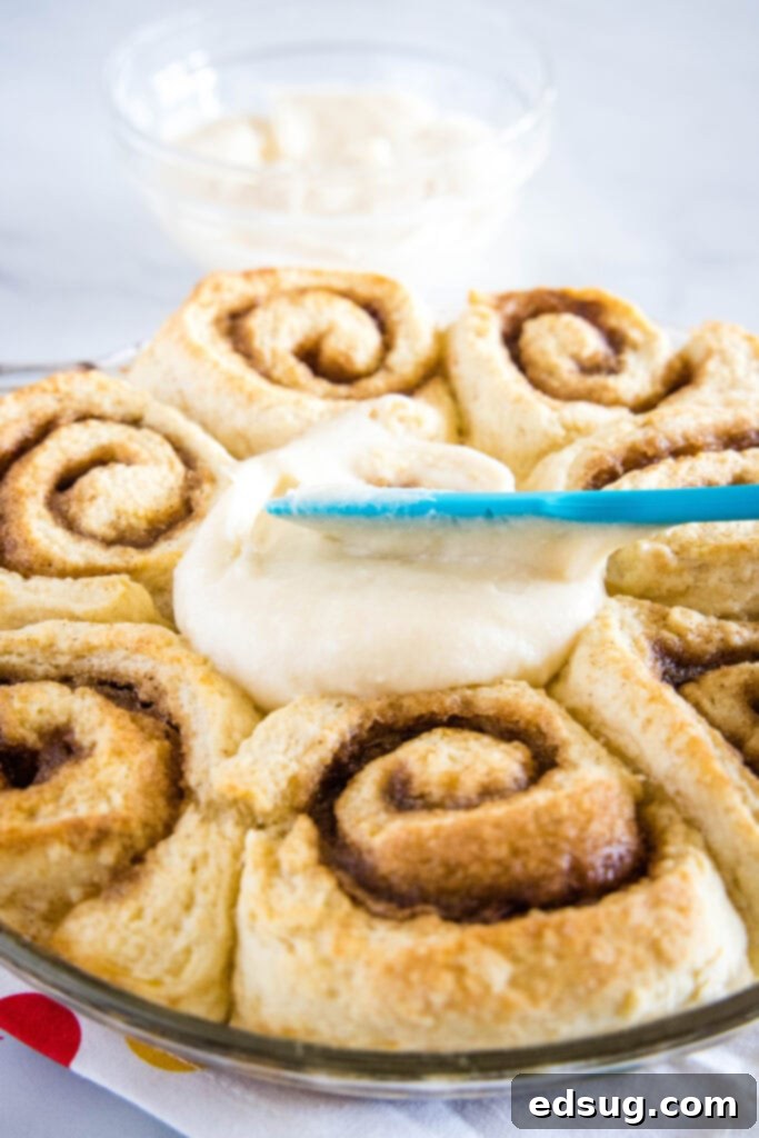 Warm Cinnamon Swirls 4 spreading frosting on cinnamon rolls