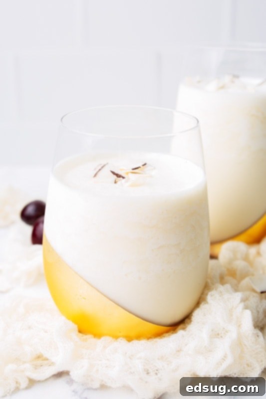 Liquid Sunshine 2 Pina Colada in a glass topped with coconut flakes and a cherry