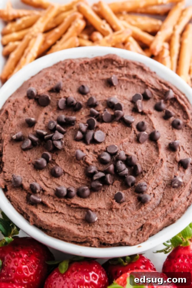 Sweet Chocolate Hummus 2 creamy chocolate hummus in a white bowl, garnished with pretzels and fresh strawberries, perfect for a healthy snack or dessert