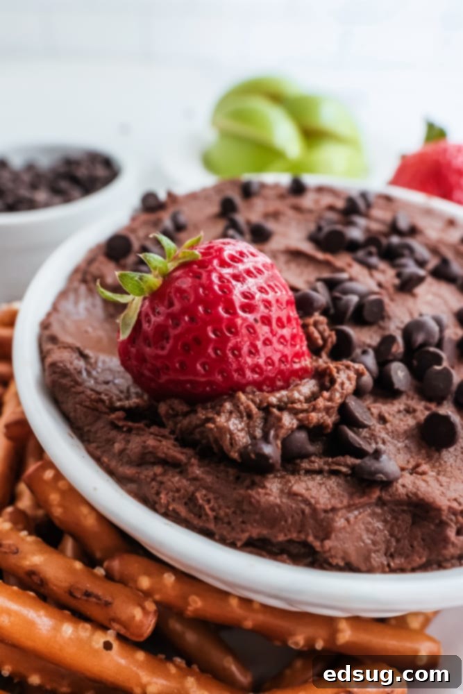 Sweet Chocolate Hummus 4 A serving of chocolate hummus in a white bowl, accompanied by fresh strawberries, highlighting its creamy texture.
