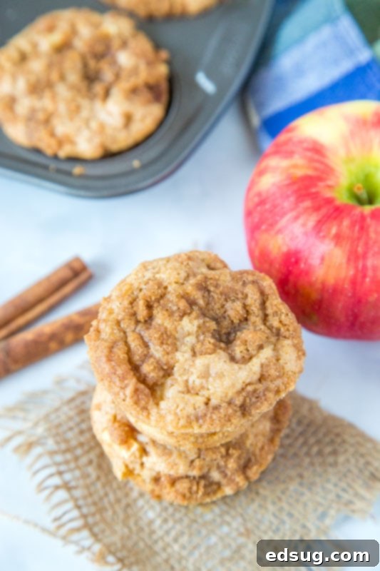 Warm Apple Cinnamon Muffins 4 A single apple cinnamon muffin next to a whole apple and cinnamon sticks