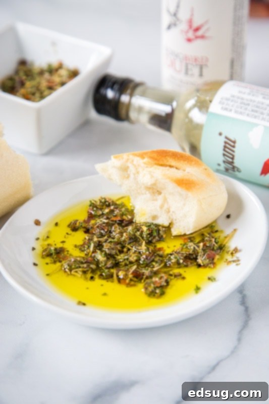 A bottle of rich olive oil beside a bowl of homemade bread dipping oil, garnished with fresh herbs and a rustic baguette slice, ready for a delightful appetizer.