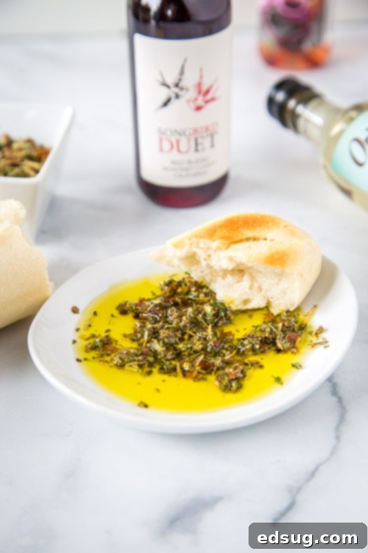 Close-up of a white bowl filled with golden olive oil and a vibrant mix of dried herbs and spices, perfect for dipping fresh bread slices.