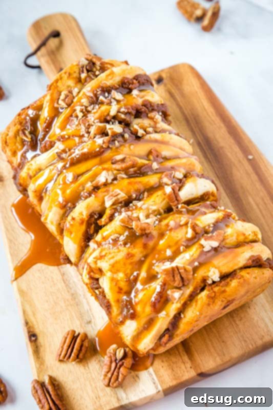 Caramel Pecan Pumpkin Pull Apart Bread garnished with extra caramel and pecans on a wooden cutting board