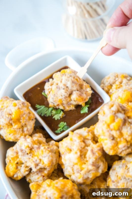 Cream Cheese Sausage Balls 4 meatball on a tooth pick being dipped in barbecue sauce