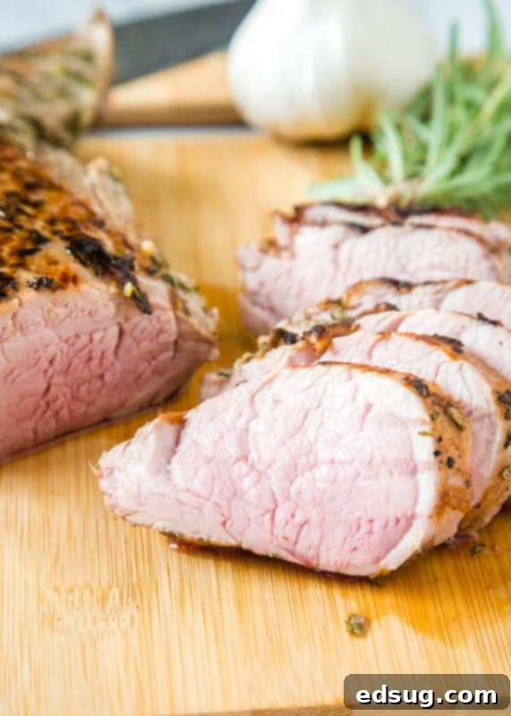 Sliced sous vide pork tenderloin revealing juicy pink interior on a cutting board
