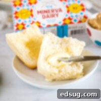 cropped image of butter being spread on a roll