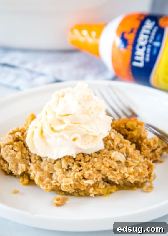 A delectable serving of pumpkin crisp on a plate, adorned with whipped cream and a fork, ready to be savored.