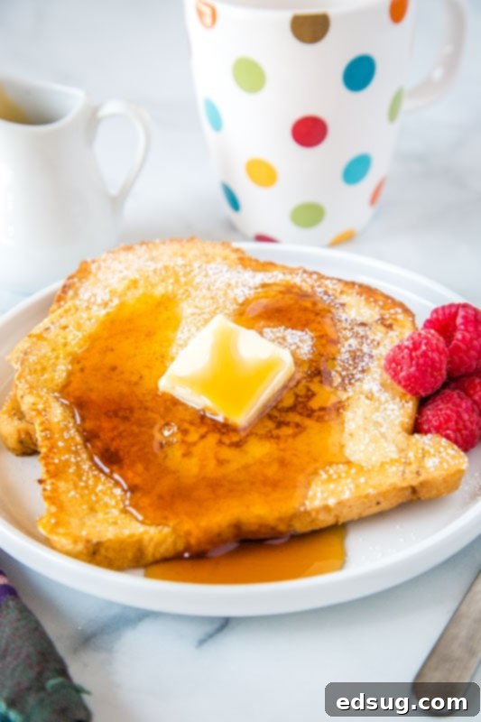 Golden Sourdough French Toast 2 Golden brown sourdough french toast slices drizzled with maple syrup, served on a white plate, ready to enjoy for breakfast.