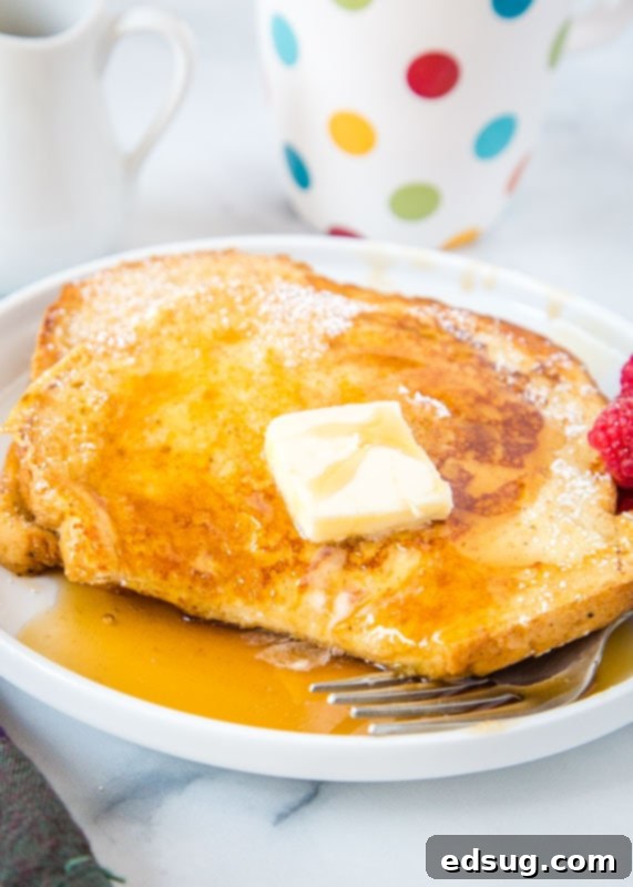 Golden Sourdough French Toast 3 A close-up of a stack of sourdough french toast with a bite taken out of the top slice, revealing its soft interior, served on a white plate.