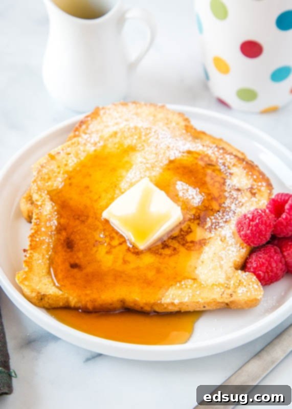 Golden Sourdough French Toast 5 Two slices of golden sourdough french toast on a plate, topped with a generous amount of butter and a drizzle of maple syrup.