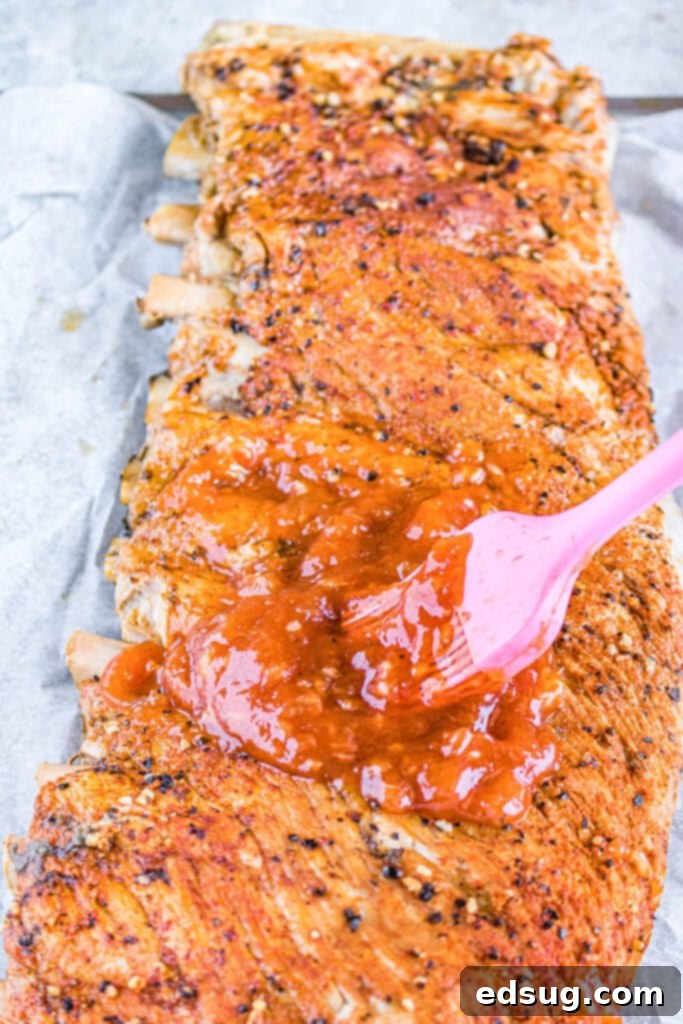 cooked ribs being brushed with barbecue sauce