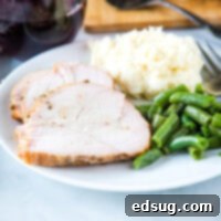 Close up of sliced smoked turkey breast on a plate with potatoes and green beans.