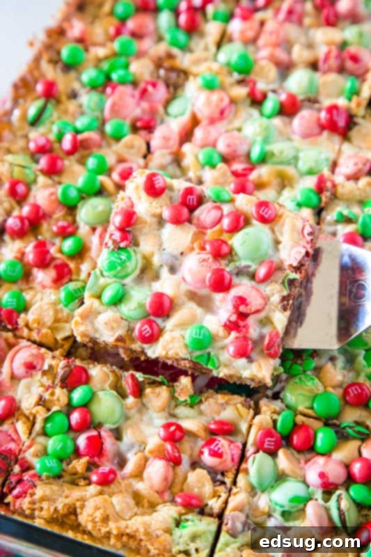 Yuletide Magic Cookie Bars 4 scooping a perfectly layered Christmas magic bar out of the pan, ready to be served
