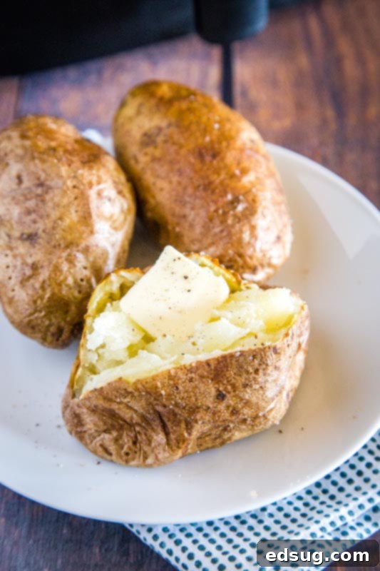 Crispy Air Fryer Baked Potato 2 baked potato cut open with butter in a plate