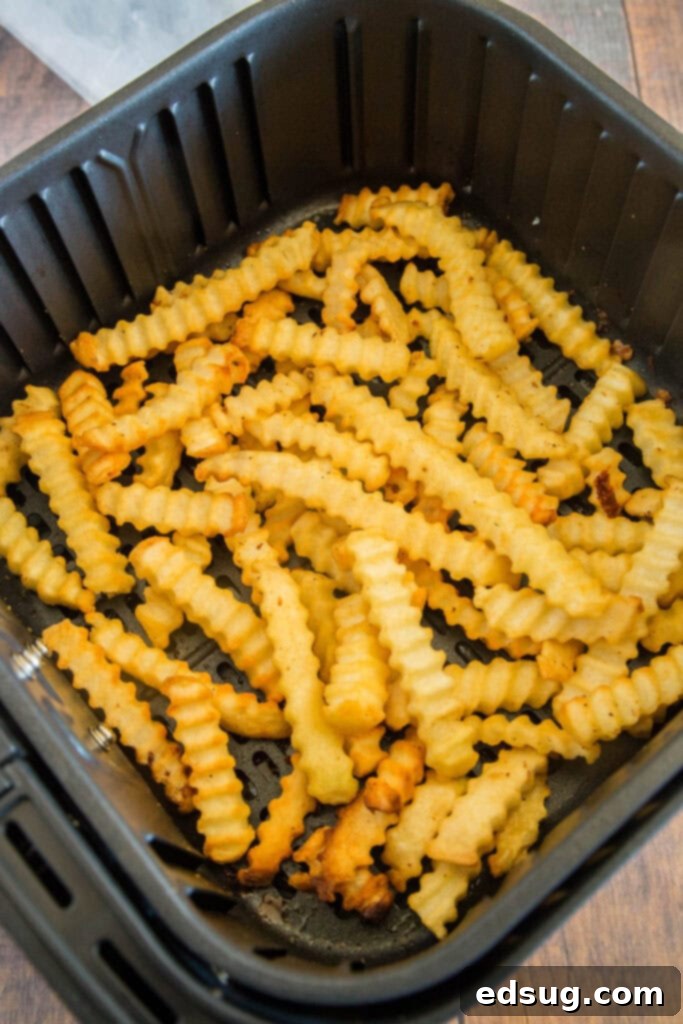 Frozen French fries neatly arranged in an air fryer basket, ready for cooking to achieve ultimate crispiness.