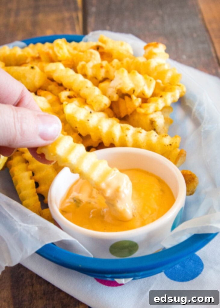 Crispy air fryer French fries dipped into a delicious, creamy sauce.