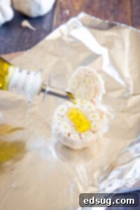 pouring olive oil on head of garlic