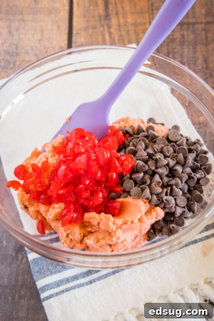 cookie dough in a bowl with chopped cherries and chocolate chips
