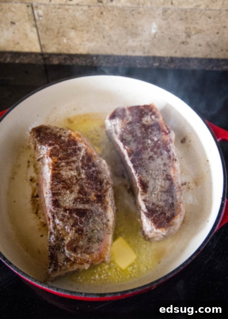 Sous Vide Steak Perfection 5 steak being seared in a hot cast iron skillet with butter on a stovetop, creating a delicious crust