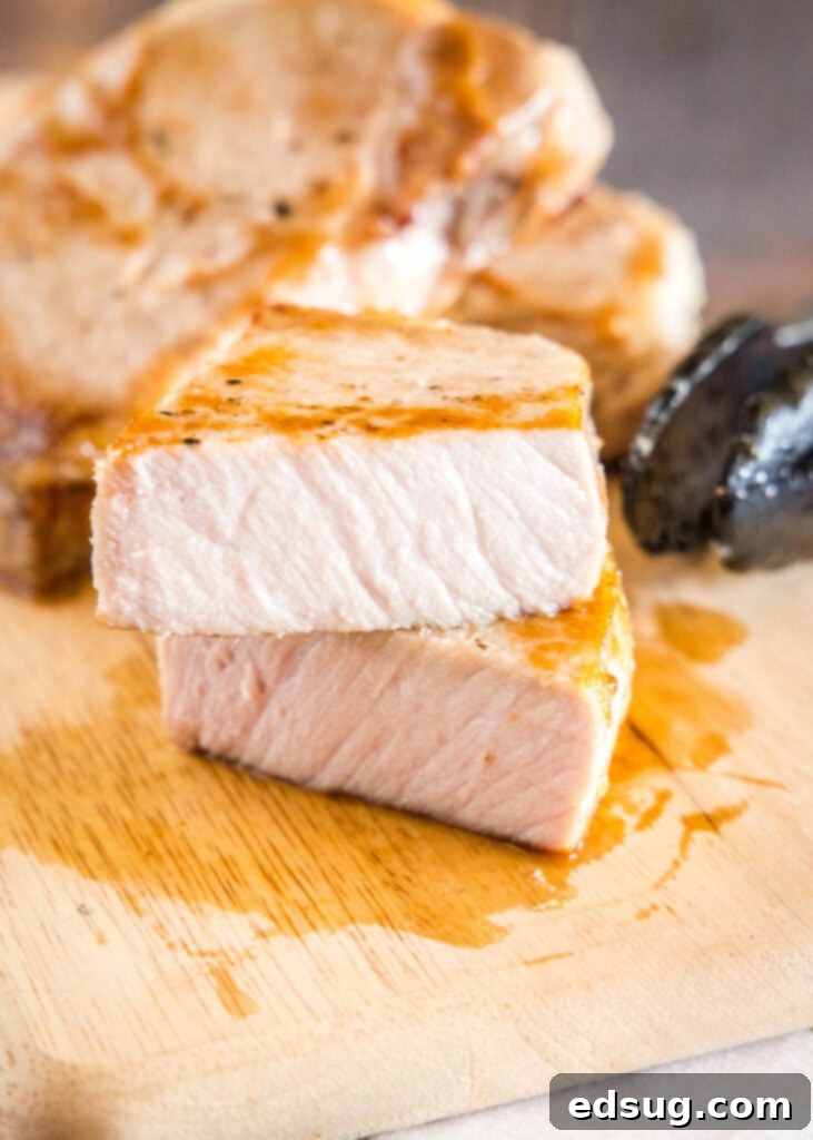 Effortlessly Perfect Sous Vide Pork Chops 2 Sliced sous vide pork chop resting on a wooden cutting board, ready to be served, showcasing its juicy interior.