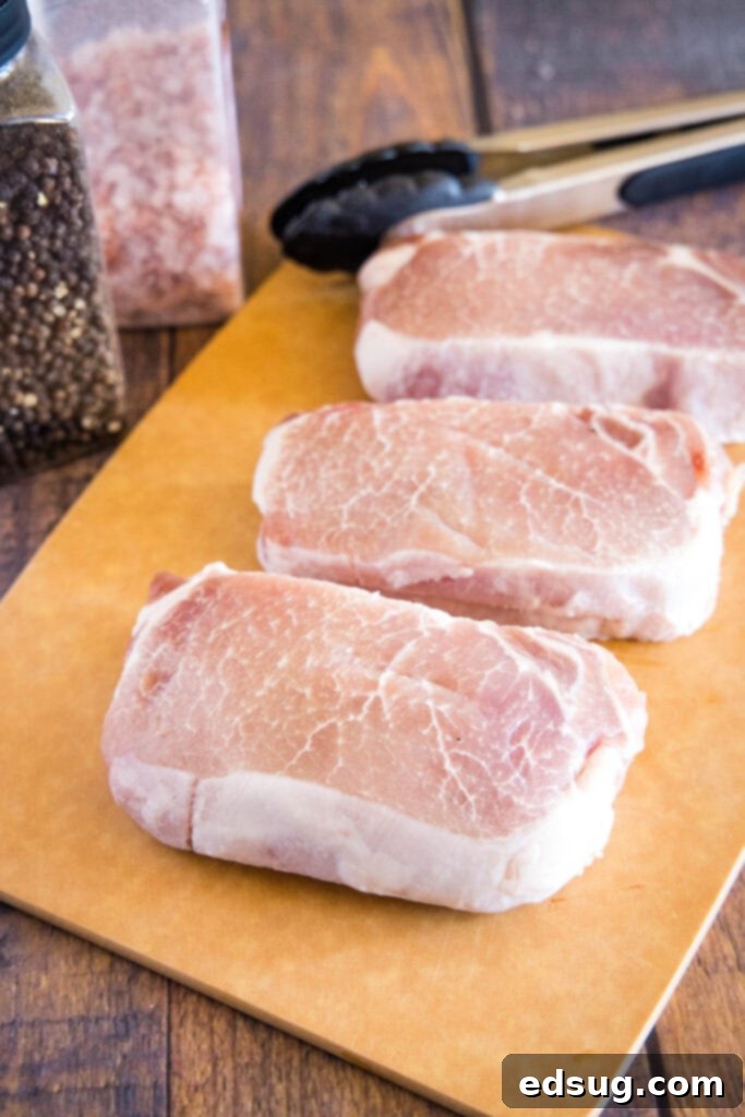Effortlessly Perfect Sous Vide Pork Chops 3 Two raw, thick-cut pork chops seasoned and ready for sous vide cooking on a cutting board.