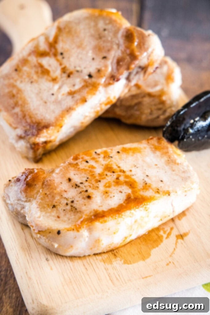 Effortlessly Perfect Sous Vide Pork Chops 8 Two fully cooked sous vide pork chops, golden brown from searing, resting on a cutting board.