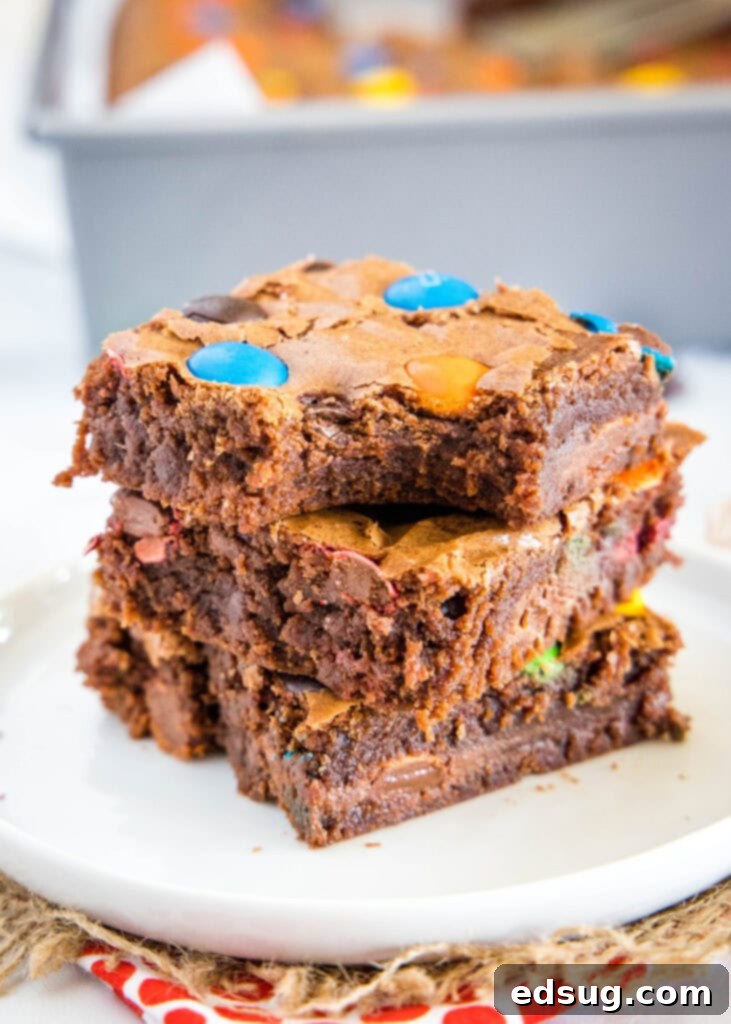 Colorful M and M Brownies 2 M&M brownies stacked with a bite out of one, showcasing the colorful candies within