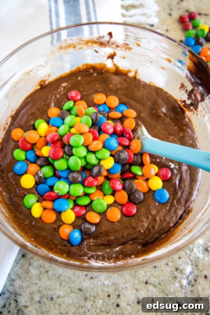 Colorful M and M Brownies 5 Adding colorful M&Ms to brownie batter in a bowl