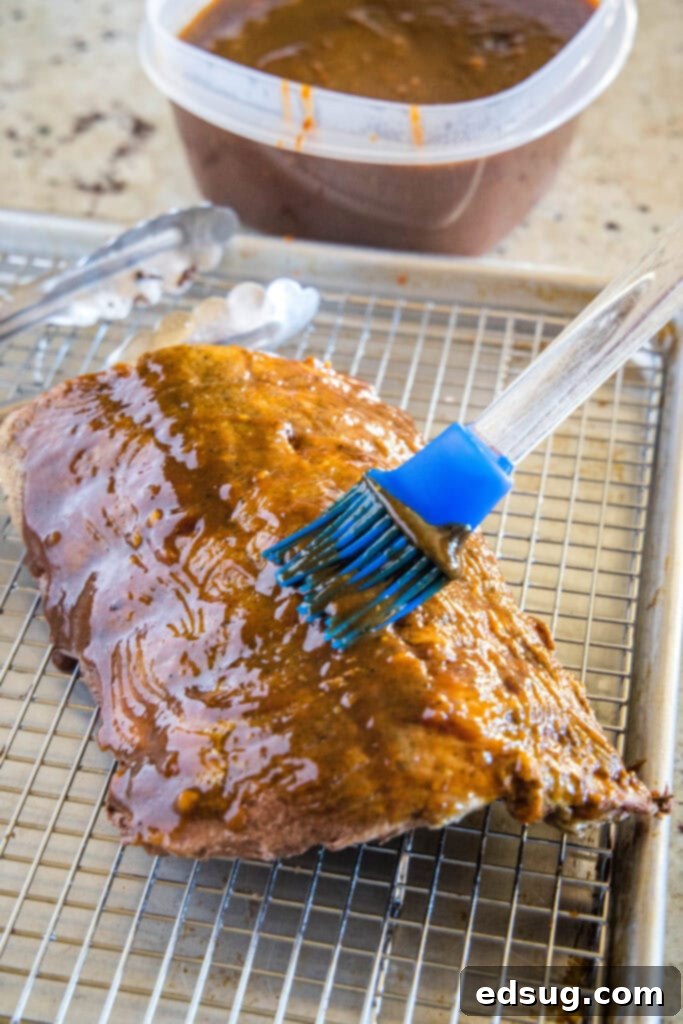 sous vide ribs on baking sheet being brushed with barbecue sauce