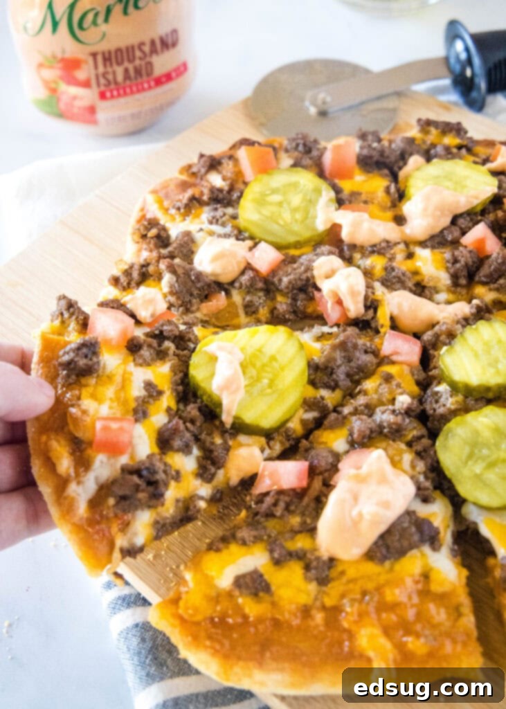 Loaded Burger Pie 2 A slice of delicious Cheeseburger Pizza being lifted from a cutting board, showcasing melted cheese and savory toppings.