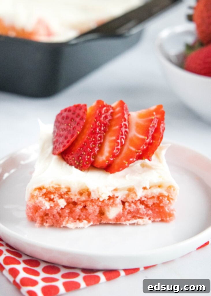 strawberry frosted brownie on a plate topped with strawberries