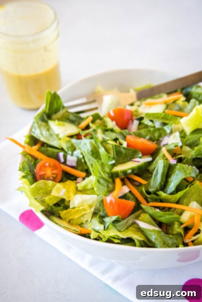 A vibrant green salad with mixed vegetables and dressing, ready to be served in a large bowl.