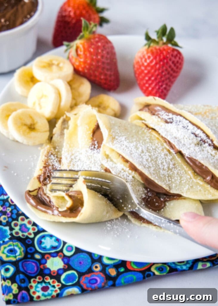 a fork cutting into fluffy Nutella crepes