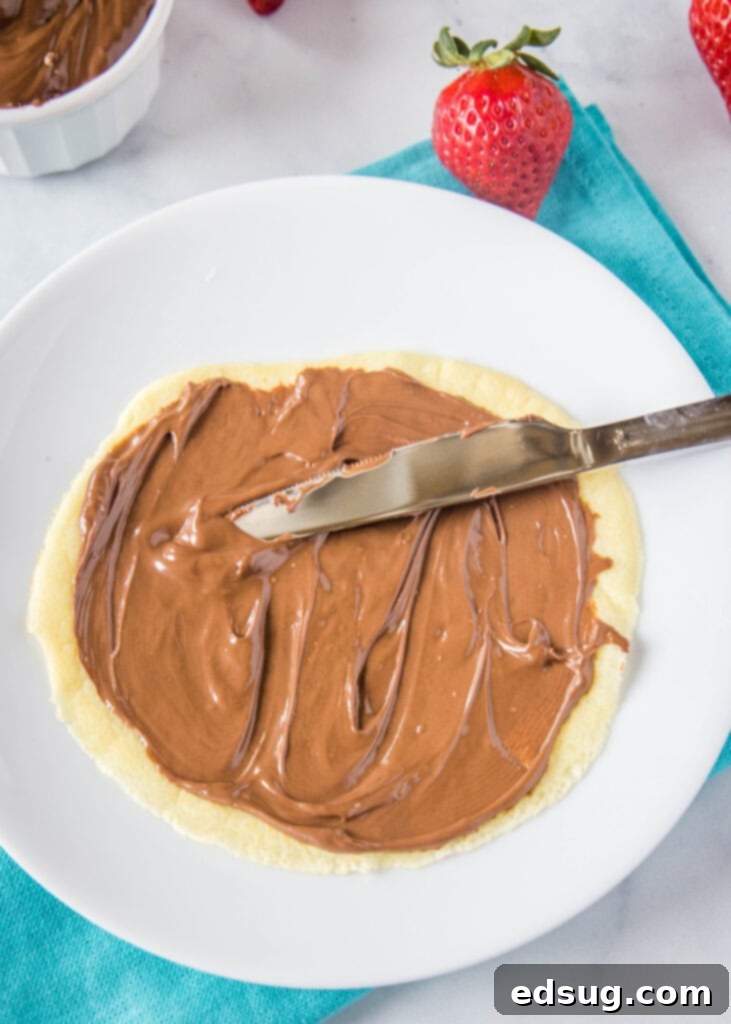 a crepe being filled with Nutella spread
