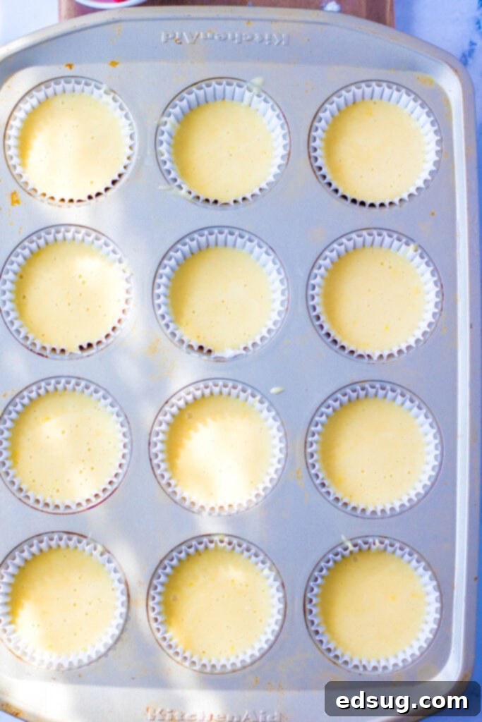 lemon cupcake batter filling a muffin tin with paper liners
