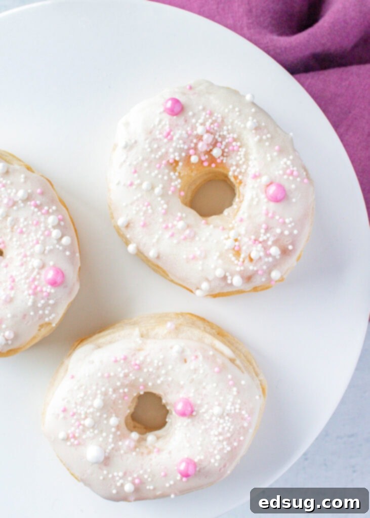Looking down on a plate with vanilla frosted air fryer donuts, garnished with colorful sprinkles.