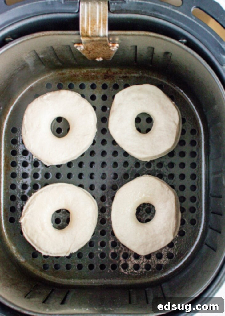 Close-up shot of golden-brown biscuit donuts cooking in an air fryer basket.