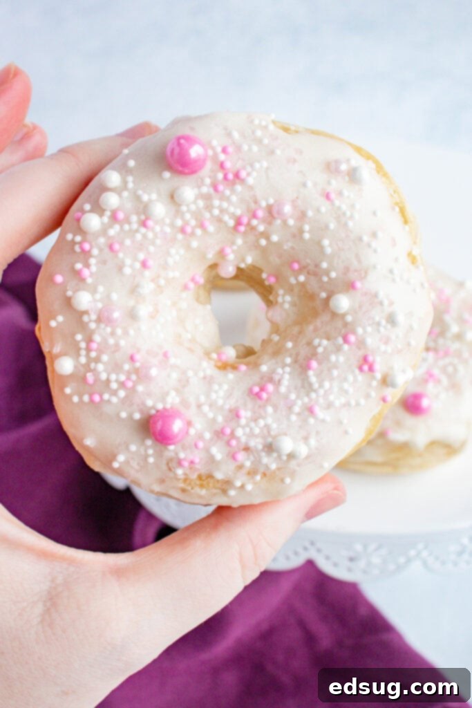 A person holding a freshly glazed and sprinkled air fryer biscuit donut.