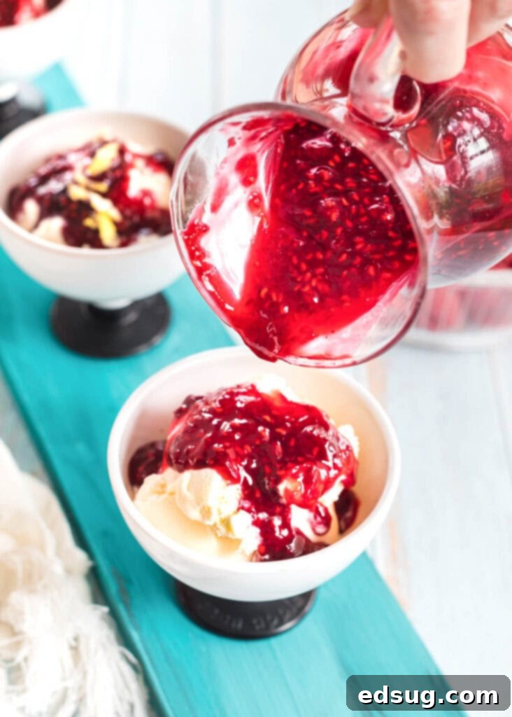 Effortless Raspberry Sauce 3 Pouring rich, homemade raspberry sauce over a scoop of vanilla ice cream, creating an irresistible dessert.