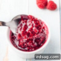 Close up shot of homemade raspberry sauce on a spoon, illustrating its perfect consistency.